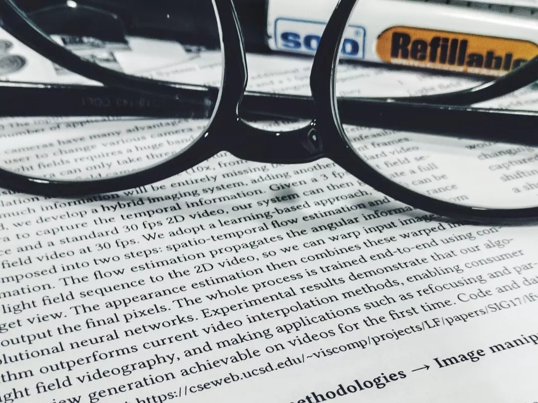 A pair of glasses and a marker sitting on top of a research paper